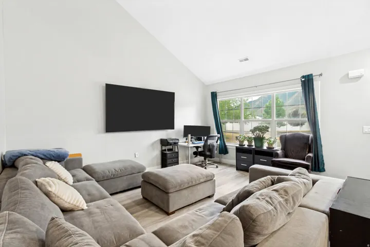 Vaulted ceiling, recessed lighting, and light wood-finish flooring