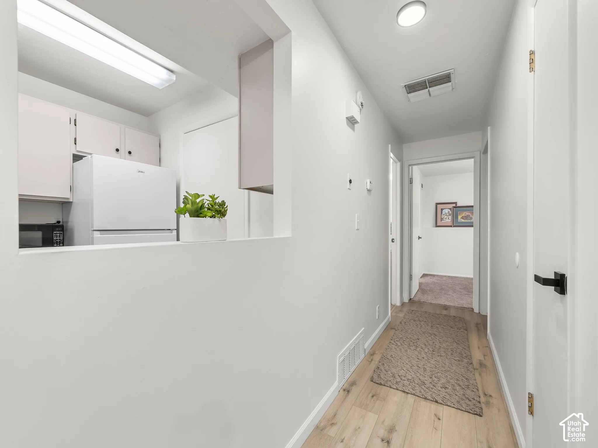 Hallway with wood-finish flooring, white walls, and a recessed ceiling light
