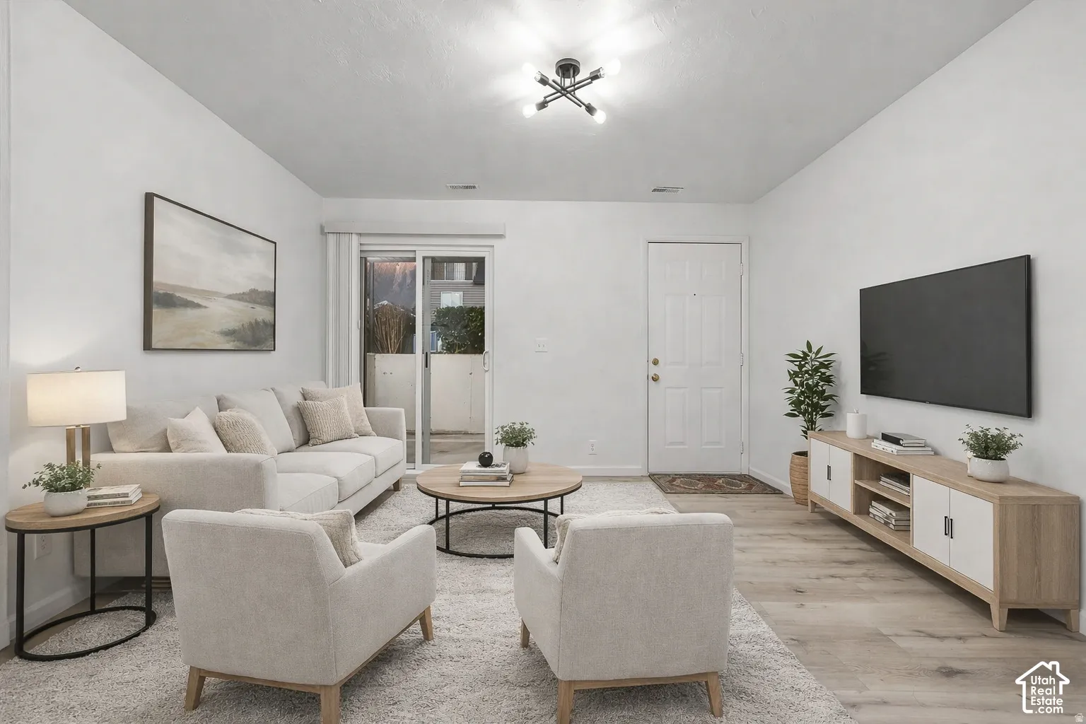 Light wood-finish flooring, a contemporary ceiling light fixture, sliding glass door access to an exterior space, and a built-in media console