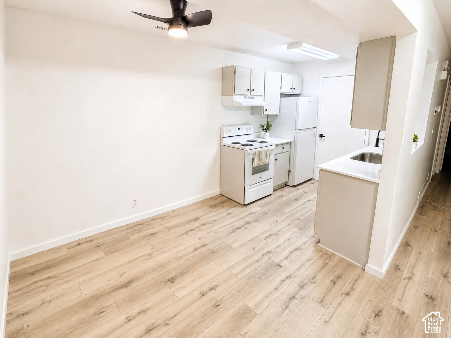 Wood-finish flooring, white walls, and a ceiling fan with integrated lighting