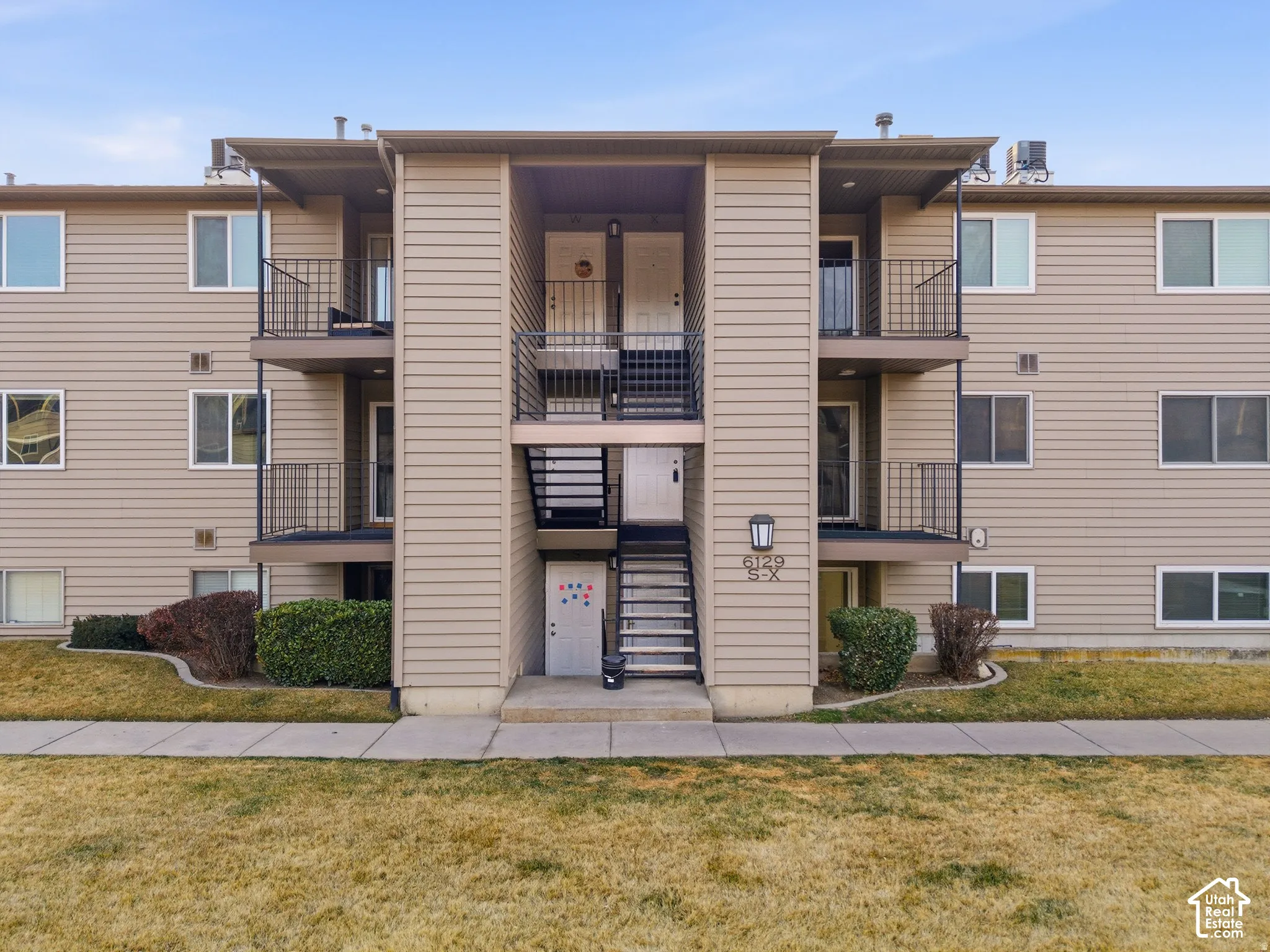 Multi-level building with horizontal siding and multiple balconies featuring black metal railings