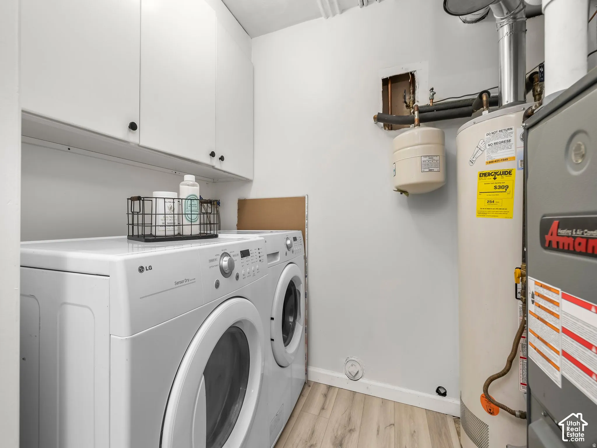 Laundry area featuring white cabinetry with black hardware, wood-finish flooring, a water heater, and a furnace