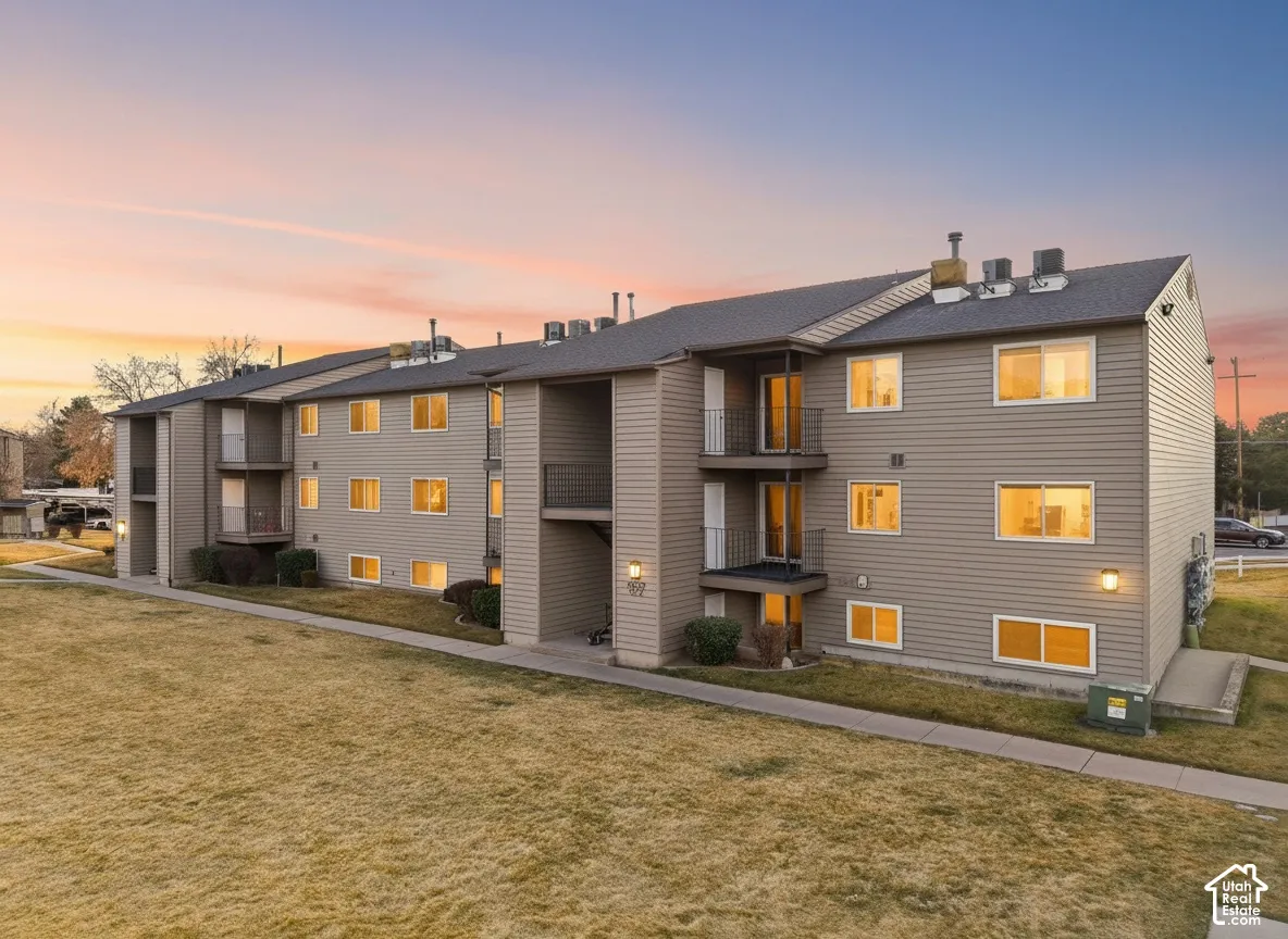 Multi-story building with neutral-toned siding, multiple windows, and a paved walkway
