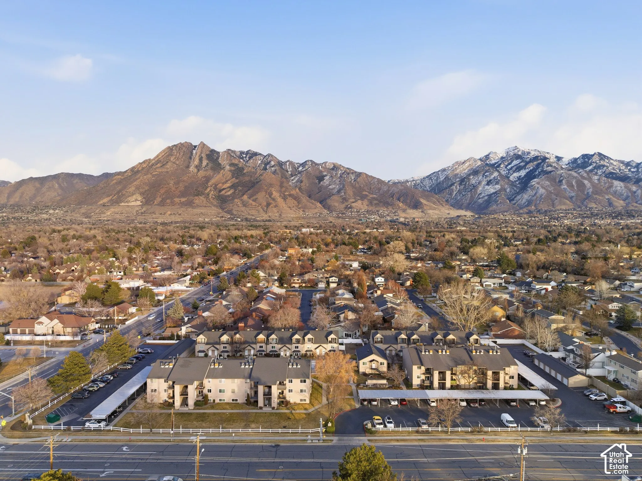 Expansive community with multi-story residential buildings, ample covered parking, and mountain scenery