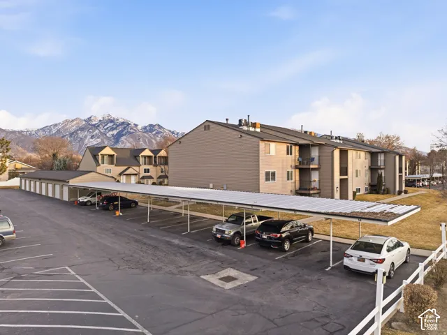 Expansive paved parking area, covered parking structures, separate garage units, multi-story residential buildings, and mountain scenery