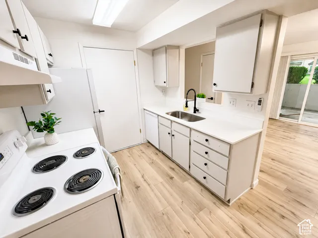 White cabinetry with black hardware, wood-finish flooring, white countertops, and a stainless steel sink with a matte black faucet