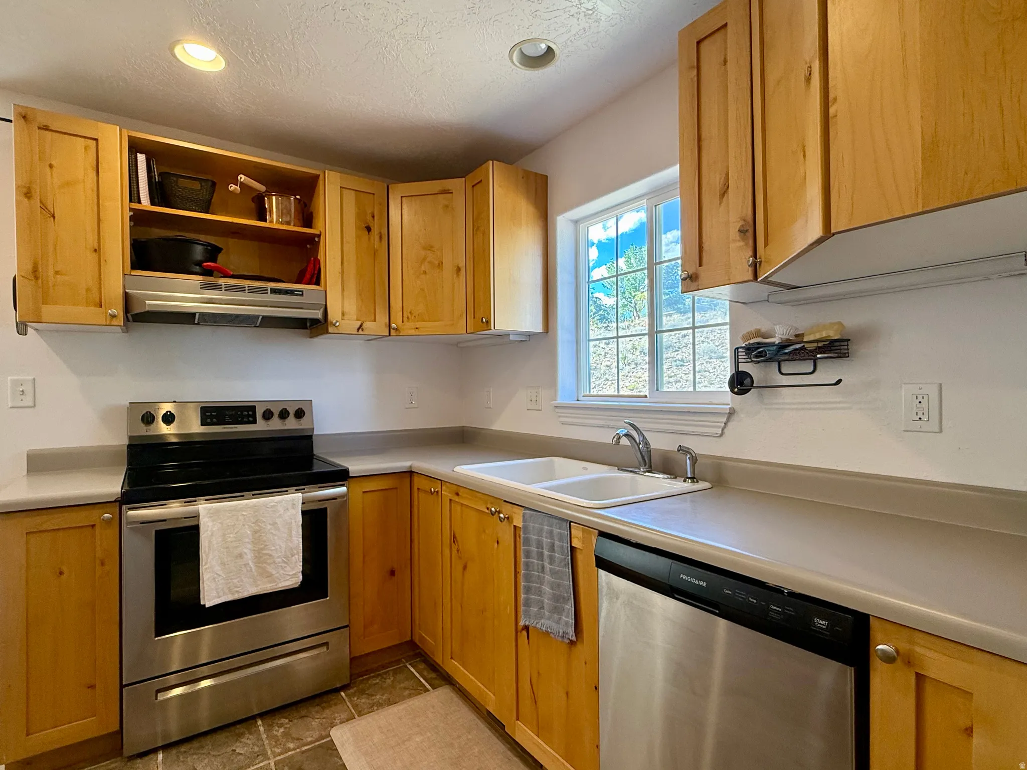 Kitchen featuring wood cabinetry, stainless steel appliances, a double basin sink, and a built-in window
