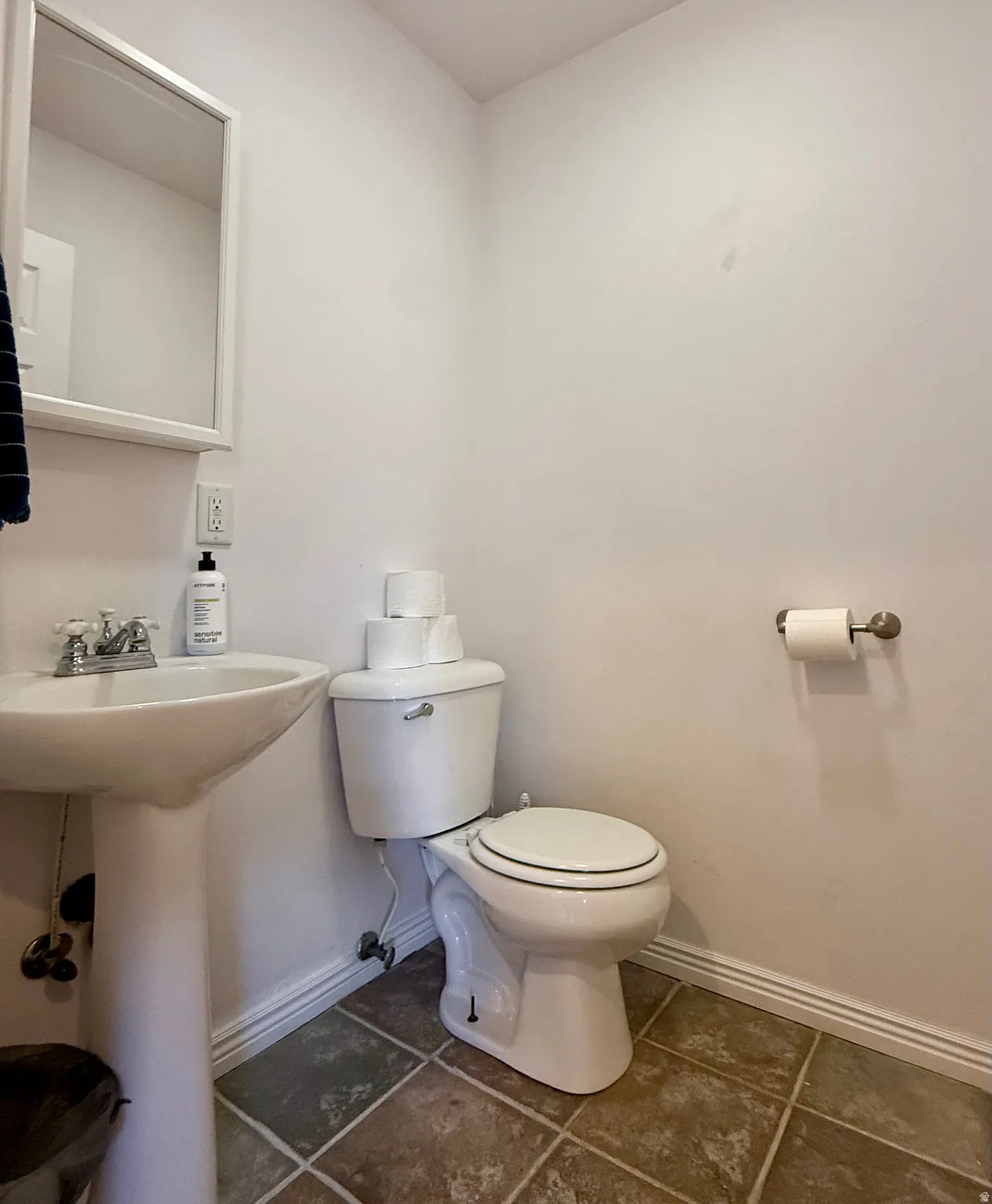 Pedestal sink with dual-handle faucet, white toilet, and tiled flooring