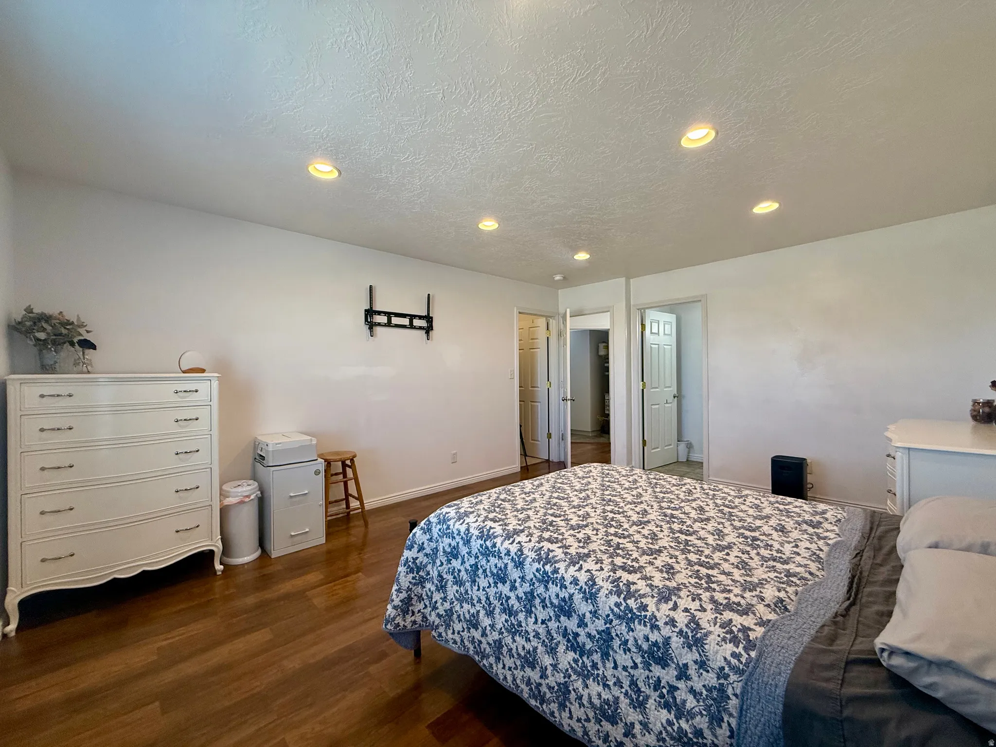 Recessed lighting, wood-finish flooring, white walls, and multiple doorways