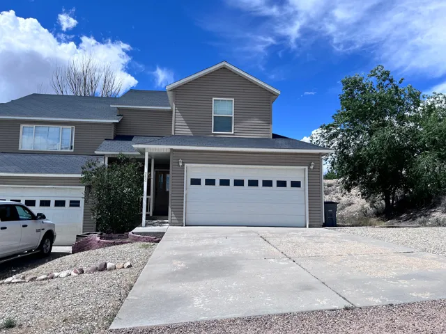 Two-story exterior with siding, attached garage with panel detailing, covered entry, and gravel landscaping