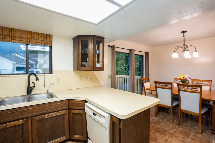 Kitchen featuring a double basin stainless steel sink, dark wood-finish cabinetry, and a built-in dishwasher