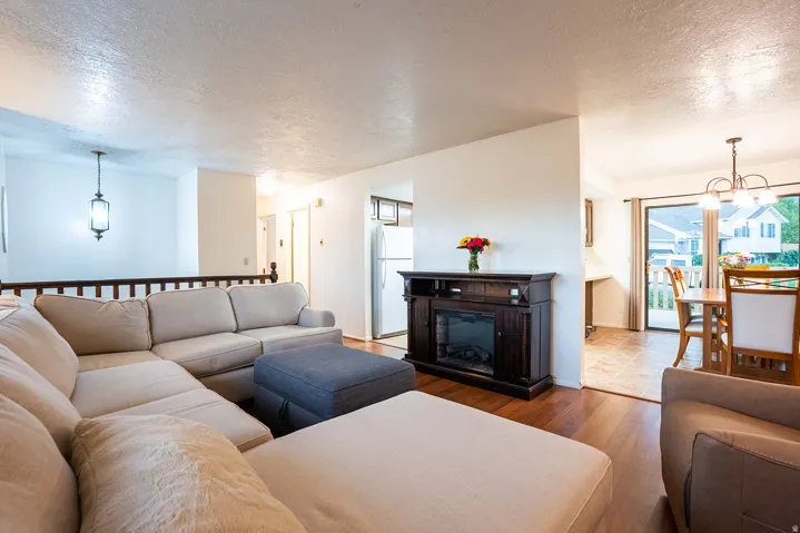 Wood-finish flooring, built-in electric fireplace, white interior walls, and a sliding glass door with exterior deck