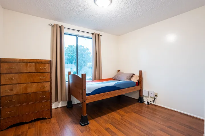 Wood-finish flooring with a window offering natural light, textured ceiling, and recessed lighting