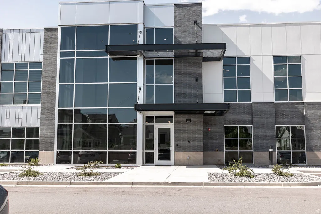 Modern exterior with expansive glass curtain walls, dark brick accents, a prominent entryway, and structured landscaping