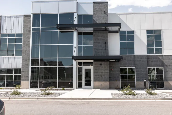 Modern exterior with expansive glass curtain walls, dark brick accents, a prominent entryway, and structured landscaping