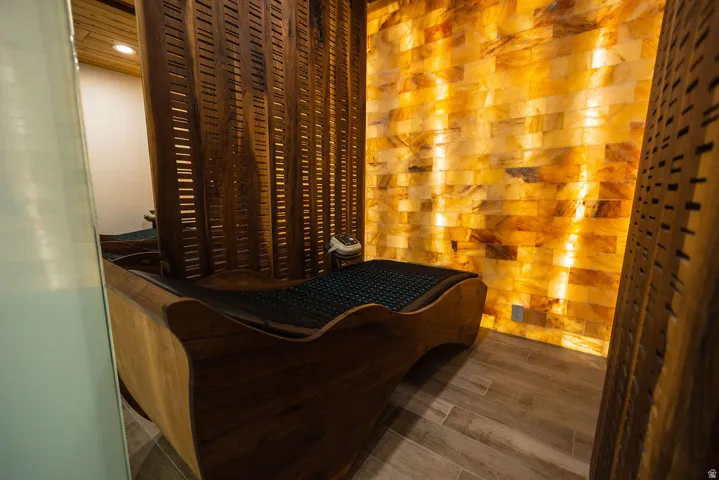 Textured wood-finish flooring, illuminated brick-pattern wall, curved wood-frame bench, and slatted wood screen partition