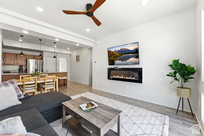 Living area featuring a wall-mounted electric fireplace, recessed lighting, wood-finish flooring, and a modern ceiling fan