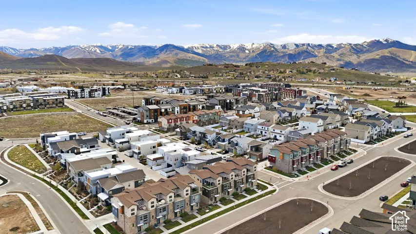 Aerial perspective of a multi-unit residential community featuring staggered rooflines, earth-toned masonry siding, paved street networks, and a backdrop of mountain ranges