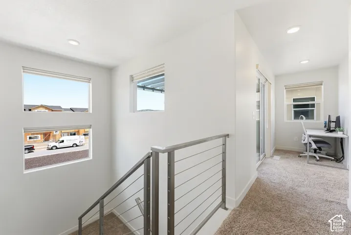 Staircase featuring a stainless steel cable railing system, recessed lighting, neutral carpeting, and multi-level windows