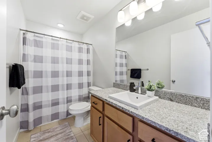 Bathroom featuring a stone-composite countertop, undermount sink with a single-handle faucet, wood cabinetry, large vanity mirror, and a full-height shower enclosure