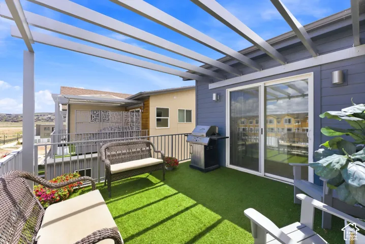 Outdoor deck featuring a metal pergola, synthetic turf flooring, horizontal plank siding, and metal railings