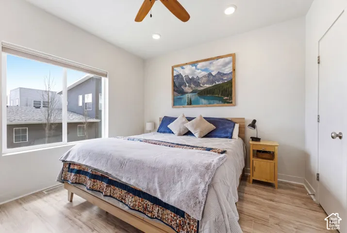 Room featuring wood-finish flooring, a large picture window, and a ceiling fan with integrated lighting