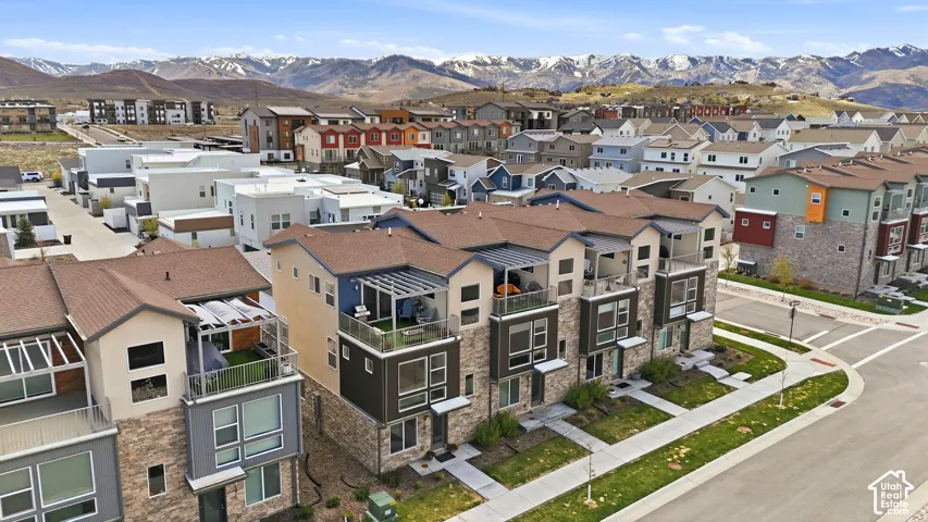 Multi-story townhome exterior featuring stone masonry, private rooftop deck, metallic pergola, and mountain backdrop