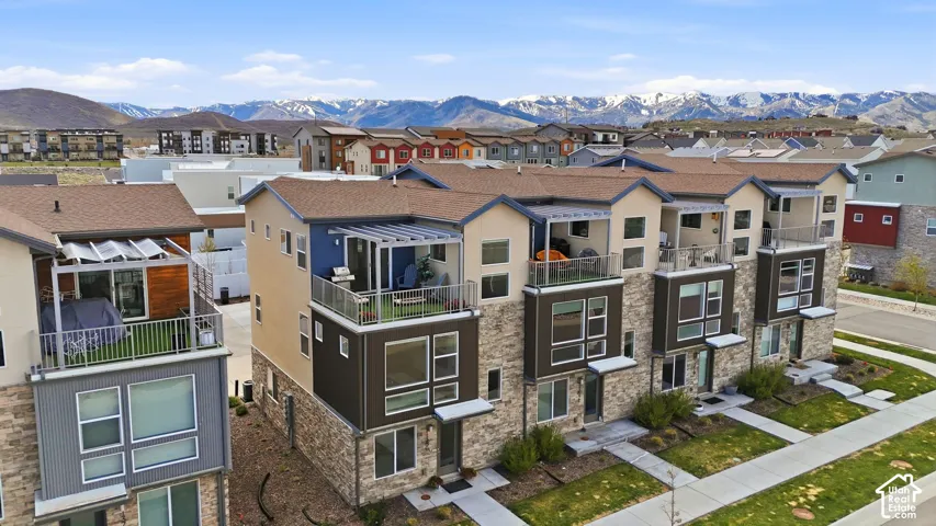Multi-level townhouse exterior featuring stacked stone veneer, private upper-level balconies, expansive windows, and a mountain backdrop