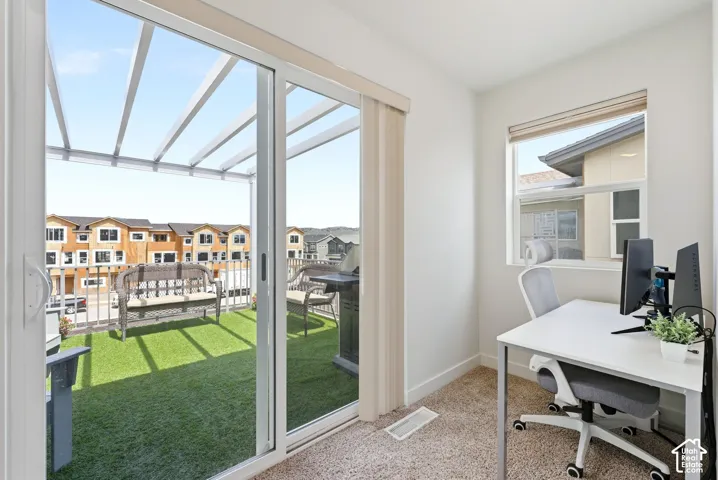 Sliding glass door opening to an elevated balcony with a pergola and synthetic turf surface