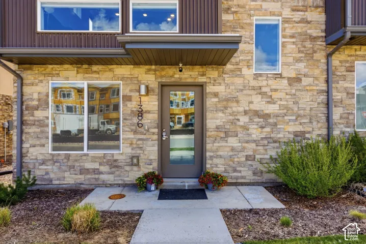 Exterior facade featuring natural stone veneer, vertical metal siding, and a covered entry with a glass-paneled door