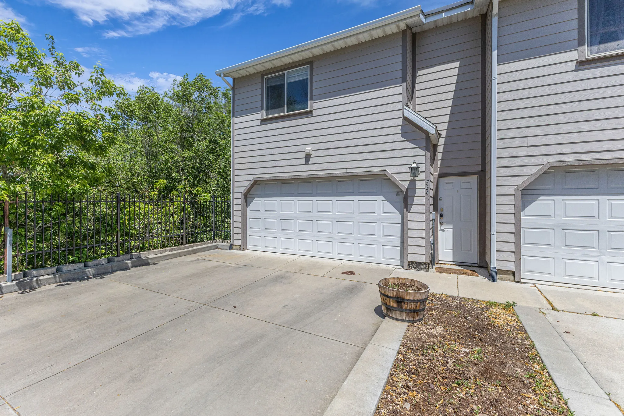 Gray siding exterior with multiple garage bays, an upper-level window, and a concrete driveway