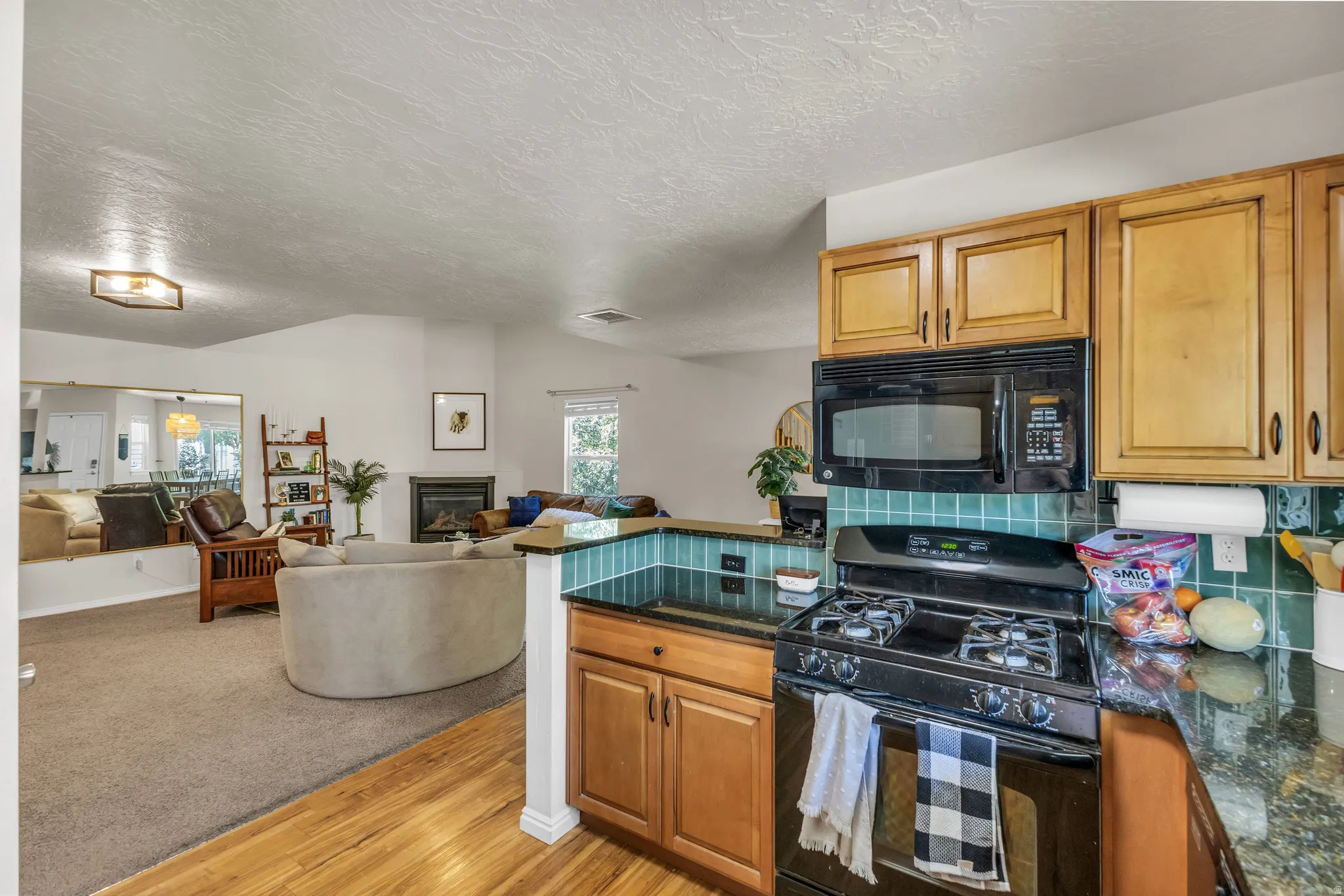 Kitchen featuring wood-finish cabinetry, dark countertops, and a tiled backsplash