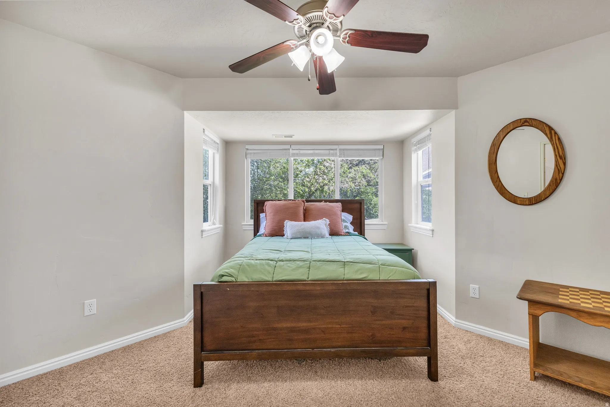 Recessed window alcove with three windows, wood-finish ceiling fan, and light neutral wall color