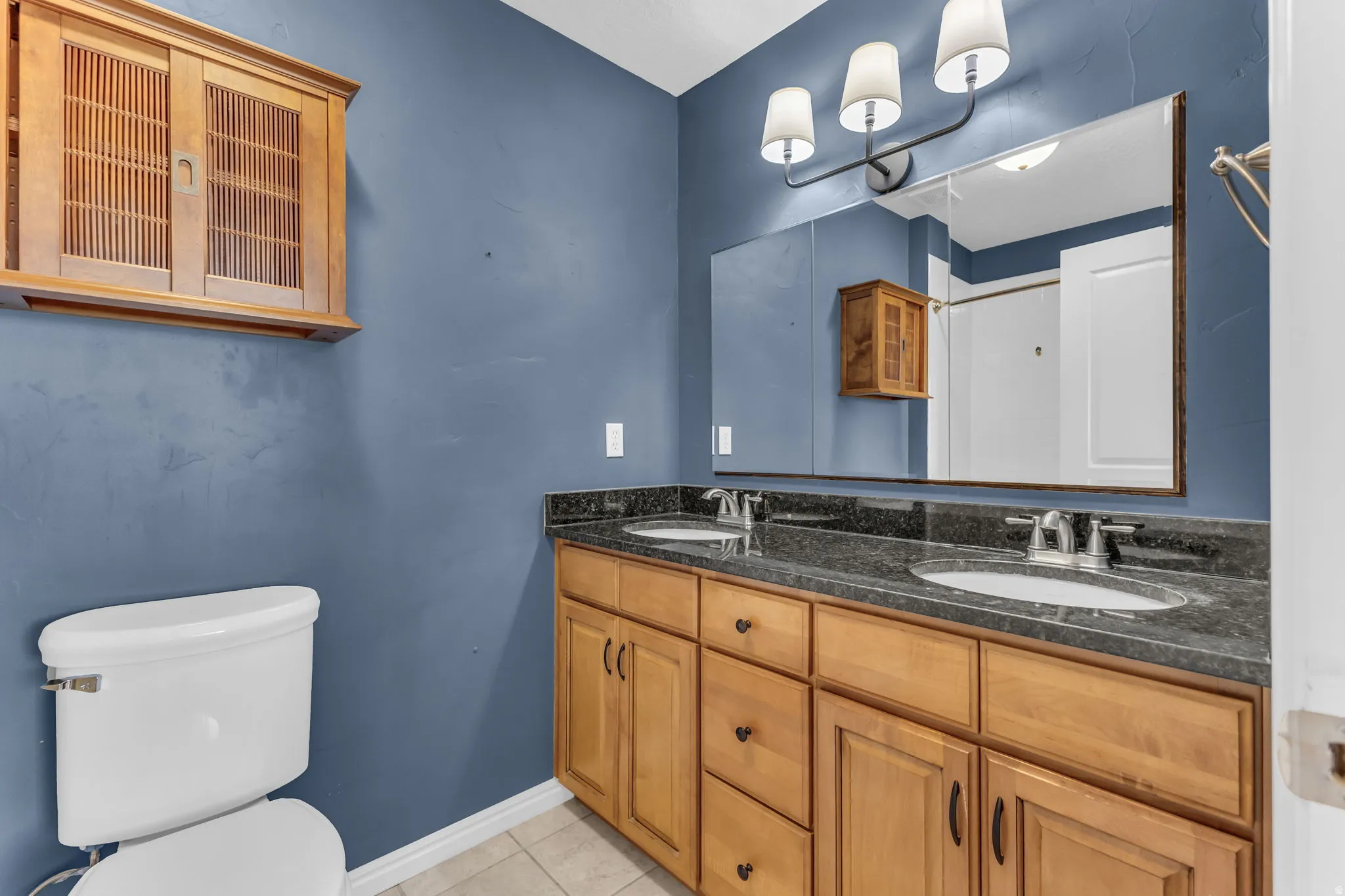 Double vanity with undermount sinks, stone countertop, and wood-finish cabinetry
