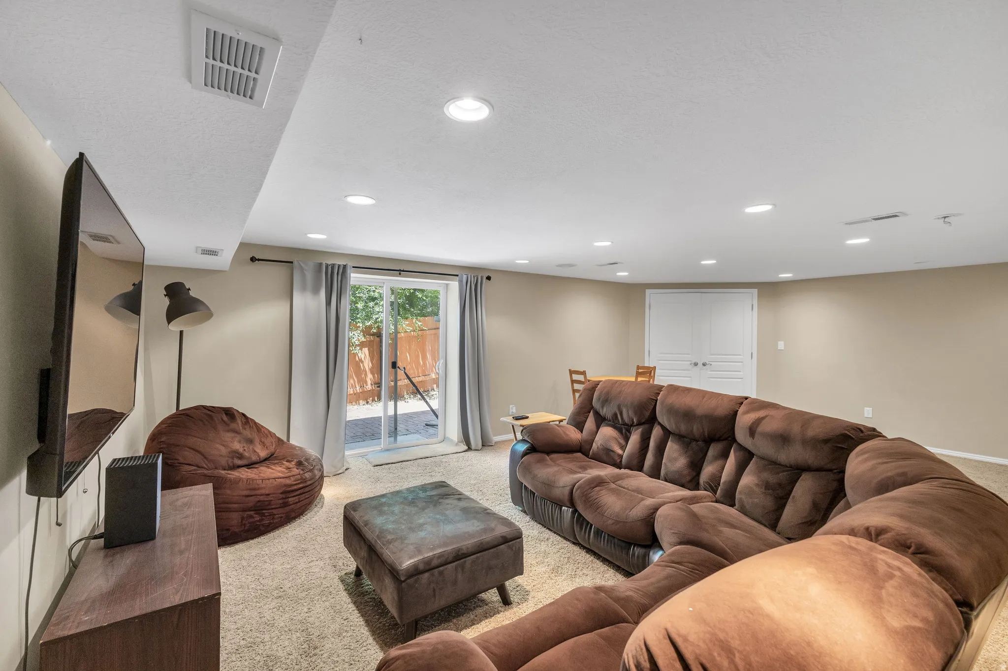 Recessed ceiling lighting, textured wall finishes, and a sliding glass door