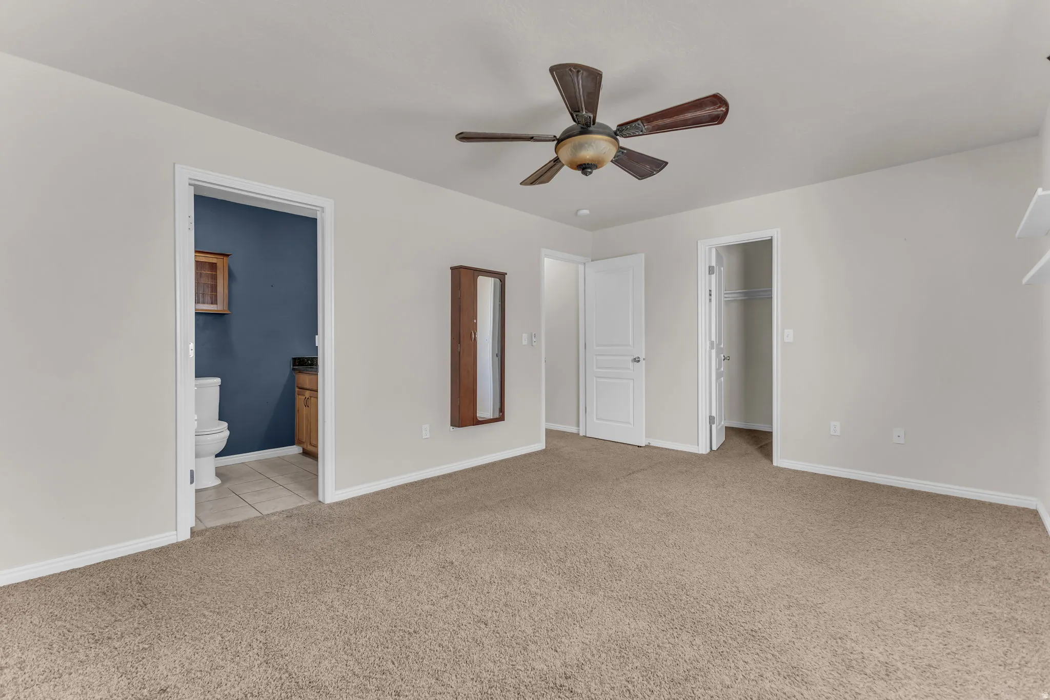 Ceiling fan with integrated lighting, soft neutral carpeting, bright white interior doors, and built-in shelving