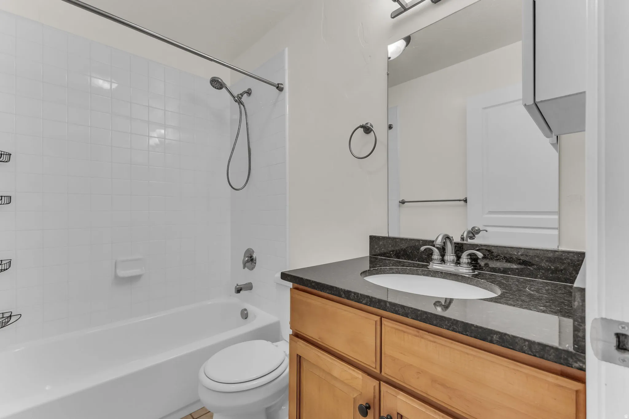 Built-in vanity with wood-finish cabinetry, dark countertop, and integrated sink