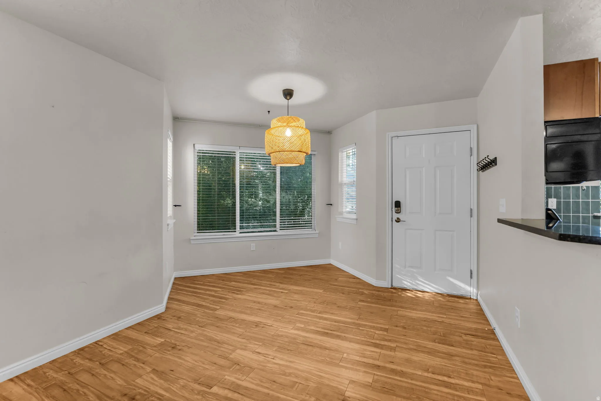 Wood-finish flooring, multiple windows with blinds, and a distinct ceiling light fixture