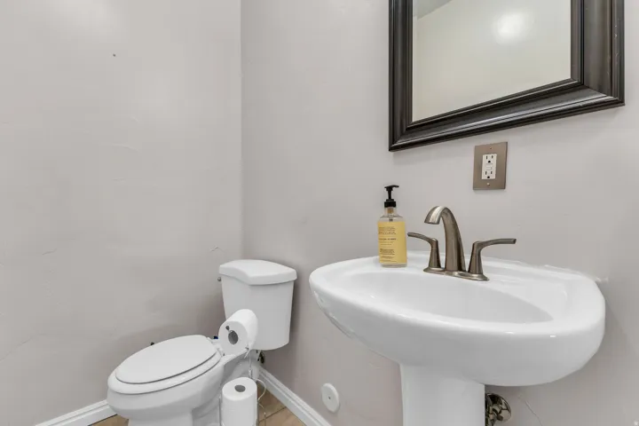 Pedestal sink with a brushed nickel faucet, framed mirror, and a white toilet