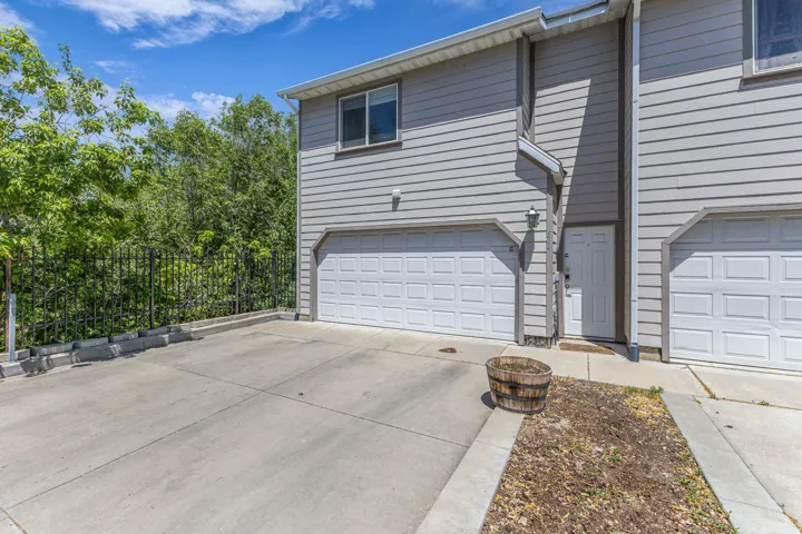 Gray siding exterior with multiple garage bays, an upper-level window, and a concrete driveway