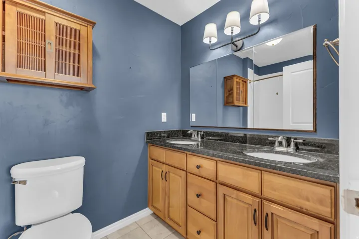 Double vanity with undermount sinks, stone countertop, and wood-finish cabinetry