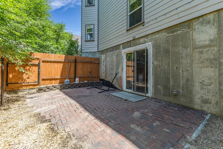 Paved patio area featuring brick pavers, surrounded by gravel and a wood privacy fence with a gate