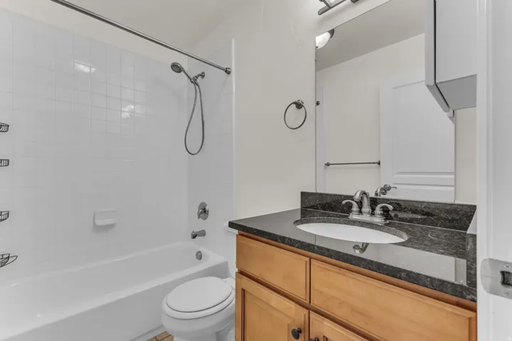 Built-in vanity with wood-finish cabinetry, dark countertop, and integrated sink