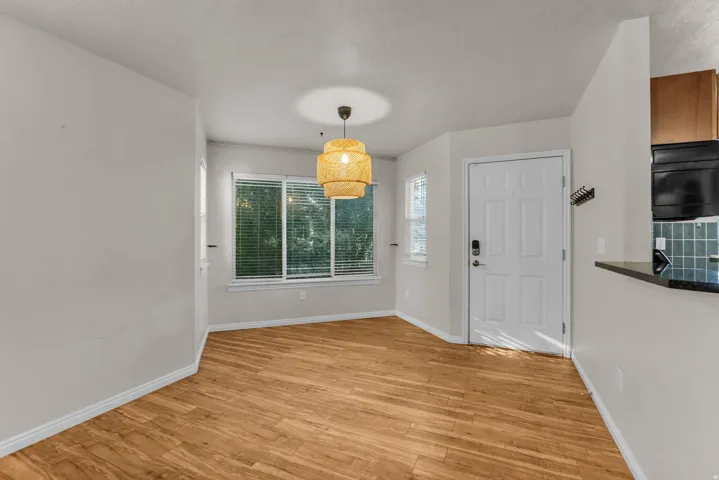Wood-finish flooring, multiple windows with blinds, and a distinct ceiling light fixture