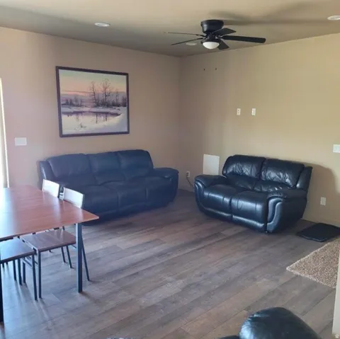 Spacious living area featuring wood-finish flooring, recessed lighting, and a ceiling fan with integrated lighting