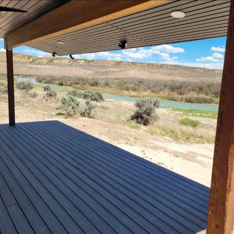 Expansive outdoor deck with dark wood-finish planking, supported by a substantial wood beam