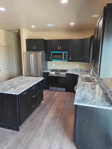 Kitchen with wood-finish flooring, dark cabinetry, and light-colored countertops
