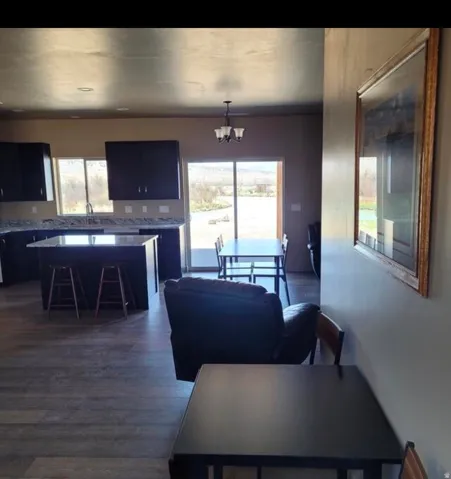 Open-concept living space with wood-finish flooring, dark wood cabinetry, light-toned countertops, and a kitchen island with seating