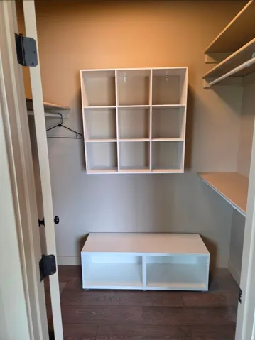 Built-in shelving, wood-finish flooring, white wall-mounted storage cubbies, and integrated lower storage