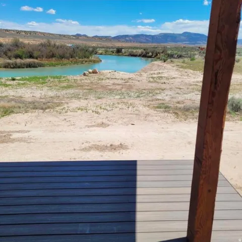 Wood-tone deck with a wood post overlooking a body of water, arid landscape, and distant mountains